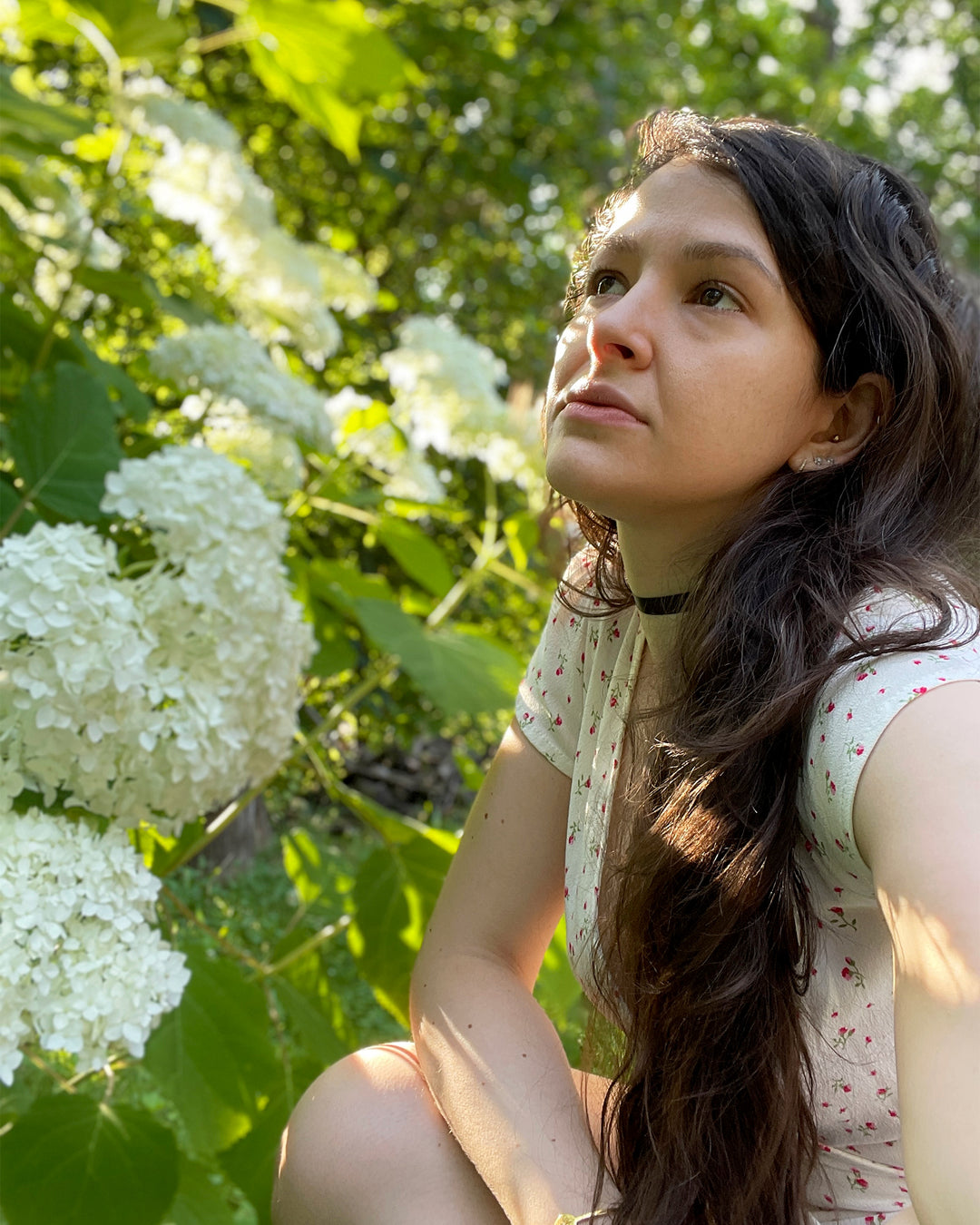 Founder of Yana Skincare, Yana Crow, in a sunlit garden.