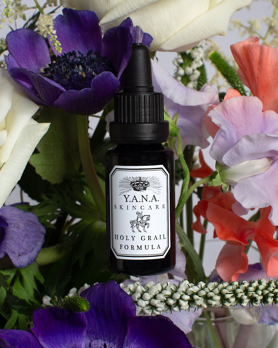 Yana Skincare Face Serum bottle floating above variously colored exotic flowers.